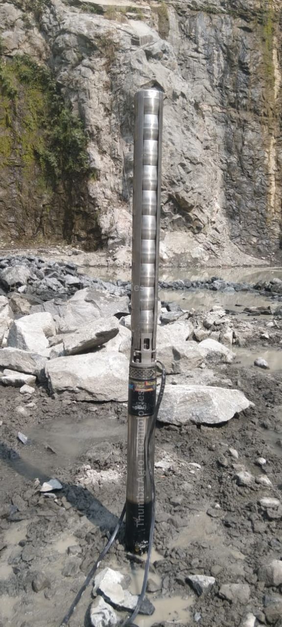 Thumba 20 HP stainless steel high discharge submersible pumpset standing in a quarry pit surrounded by blast rubble and slurry water