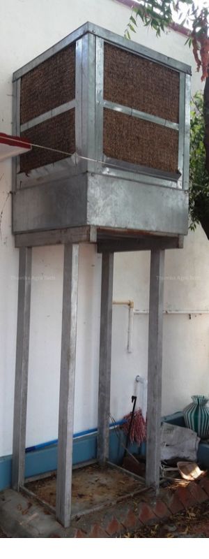 Thumba E-Cooler unit mounted on a raised steel stand outside a sericulture rearing shed, with wood wool pads visible